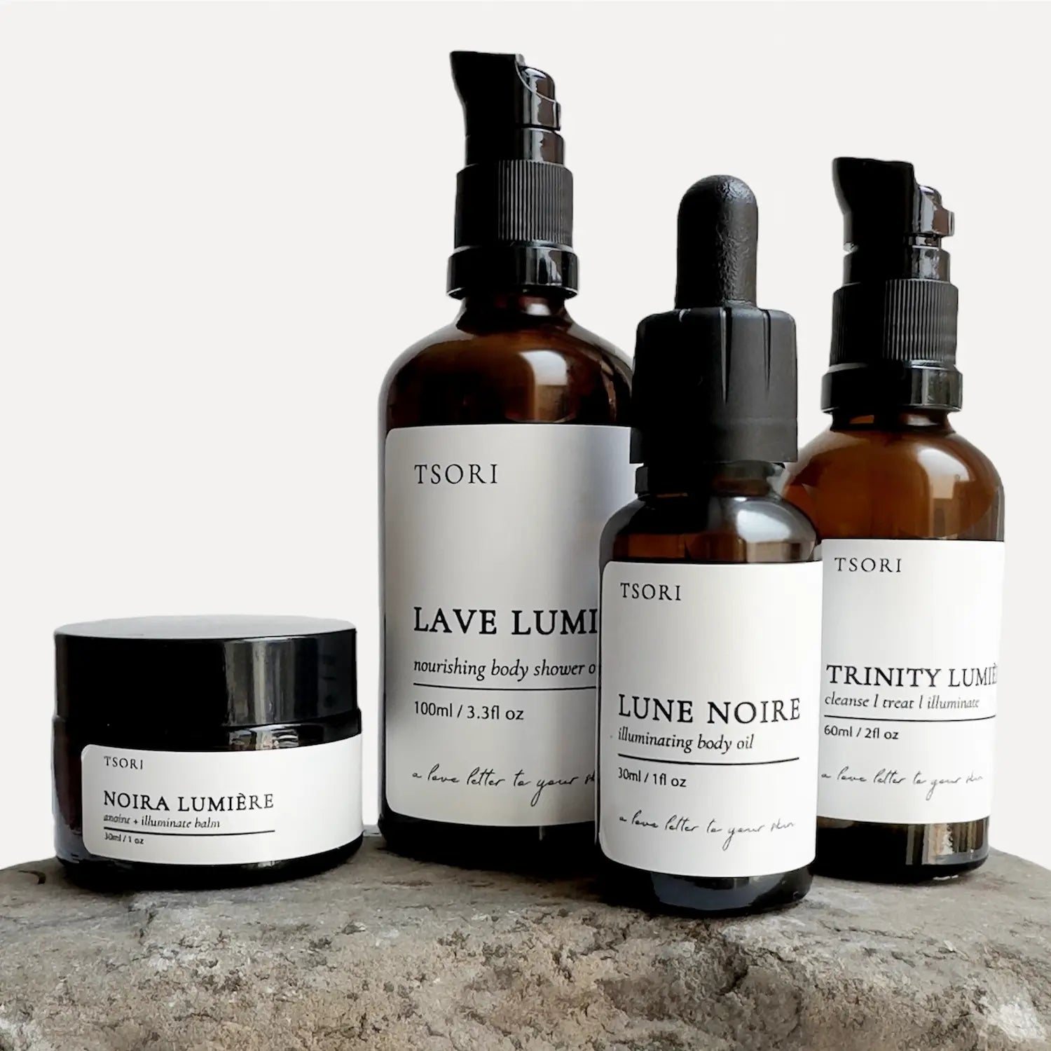 Collection of TSORI minimalist waterless skincare products on a stone surface with a white background