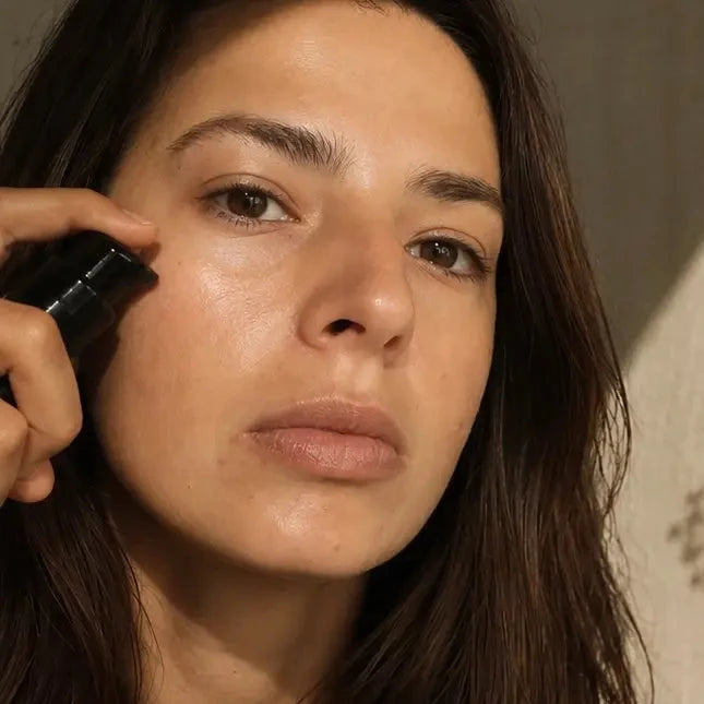Woman applying makeup with a brush in a warm-toned setting