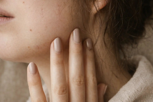 Close-up of calm, natural skin with gentle touch in soft light.