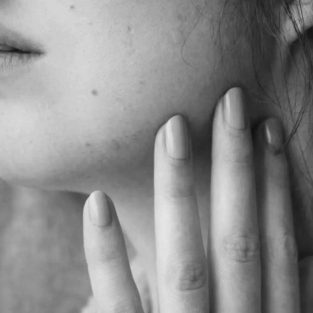 Black and white close-up of a hand covering part of a face