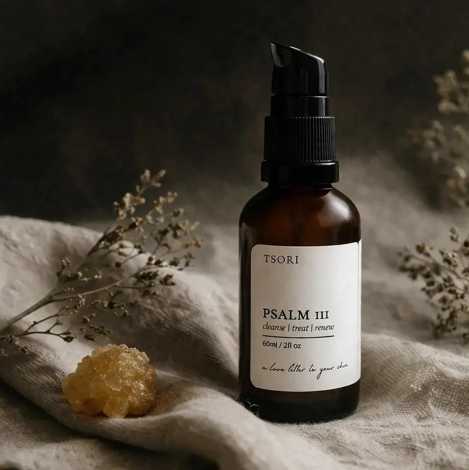 Brown bottle with black cap labeled 'Psalm III' on a textured fabric background with dried plants.