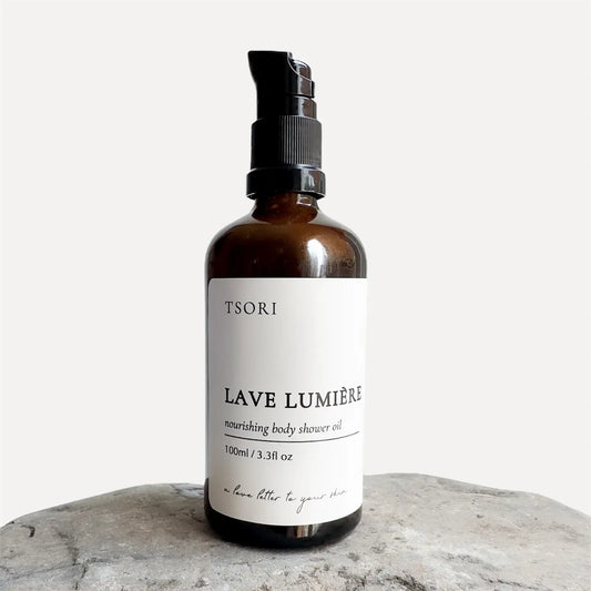 Bottle of TSORI Lave Lumiere body shower oil on a stone surface with a white background