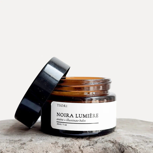 Jar of 'Noira Lumérie' balm with a black lid on a light background