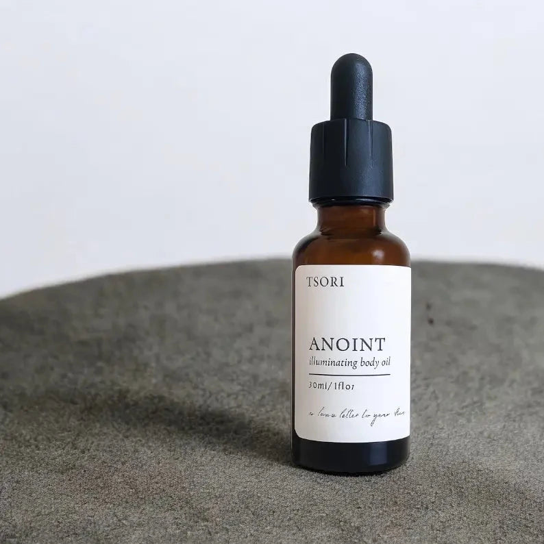 Bottle of ISORI Anoint oil on a gray surface with a white background