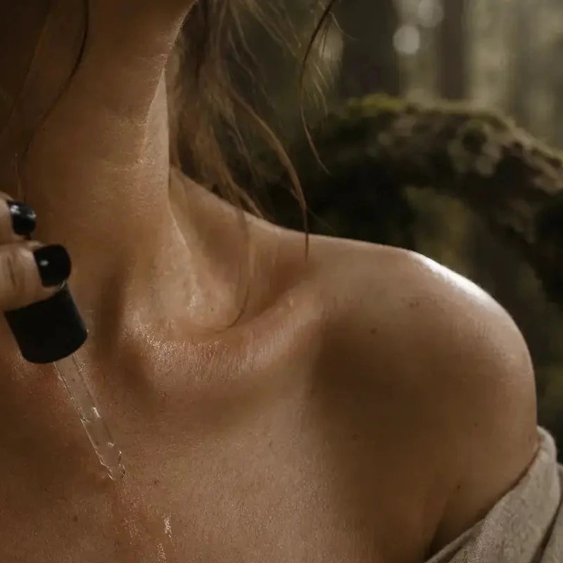 Person applying a black substance to their neck with a brush in a forest setting