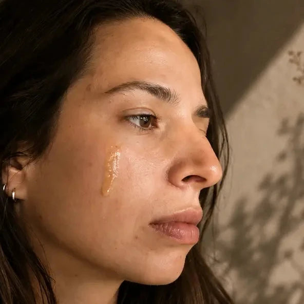 Woman with a drop of liquid on her cheek against a neutral background
