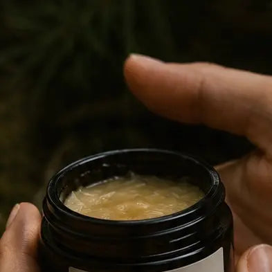 Person holding a jar of cream or paste with a blurred background